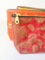 Load image into Gallery viewer, Close up of four waxed canvas pouches with gold brass zipper in a row in red orange, yellow, and again red in the back. 
