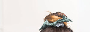 Top of a woman's head with her hair in a bun and tied with a bow hair scrunchie. 