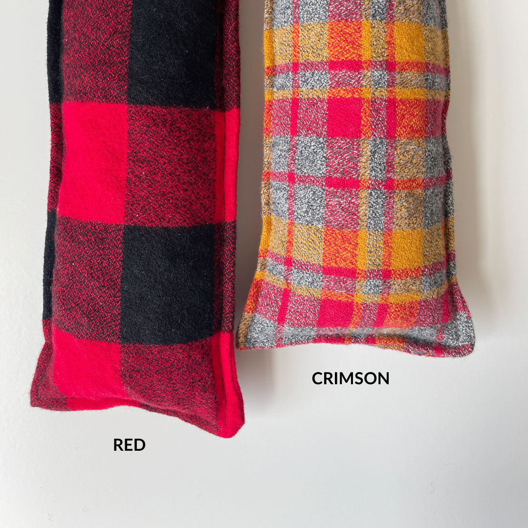 2 cherry pit warmers in plaid from left to right with text: Red: large buffalo plaid in red and black. Crimson: small plaid in shades of red, orange, and grey. 