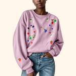 Load image into Gallery viewer, Person wearing a light purple sweatshirt with colorful fruit designs on a white background
