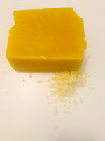 Load image into Gallery viewer, A small pile of beeswax pellets sits next to a block of beeswax on a white background. 
