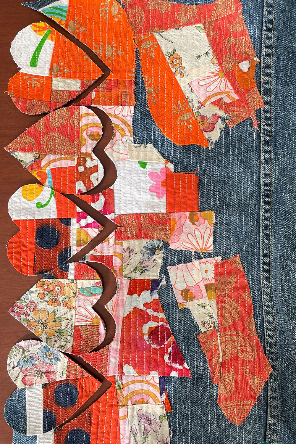 A column of heart shaped patches that are crumb quilted onto denim fabric. 