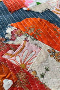 Close up of crumb quilted fabric sewn on to denim. Top stitched with rows of white stitches spaced about 1/4" away. 