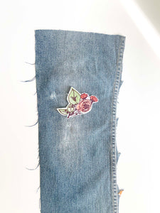 Cut denim leg with machine embroidered rose bush patch on the knee. 