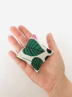 Load image into Gallery viewer, A small square fabric hand warmers sits on an open palm. 
