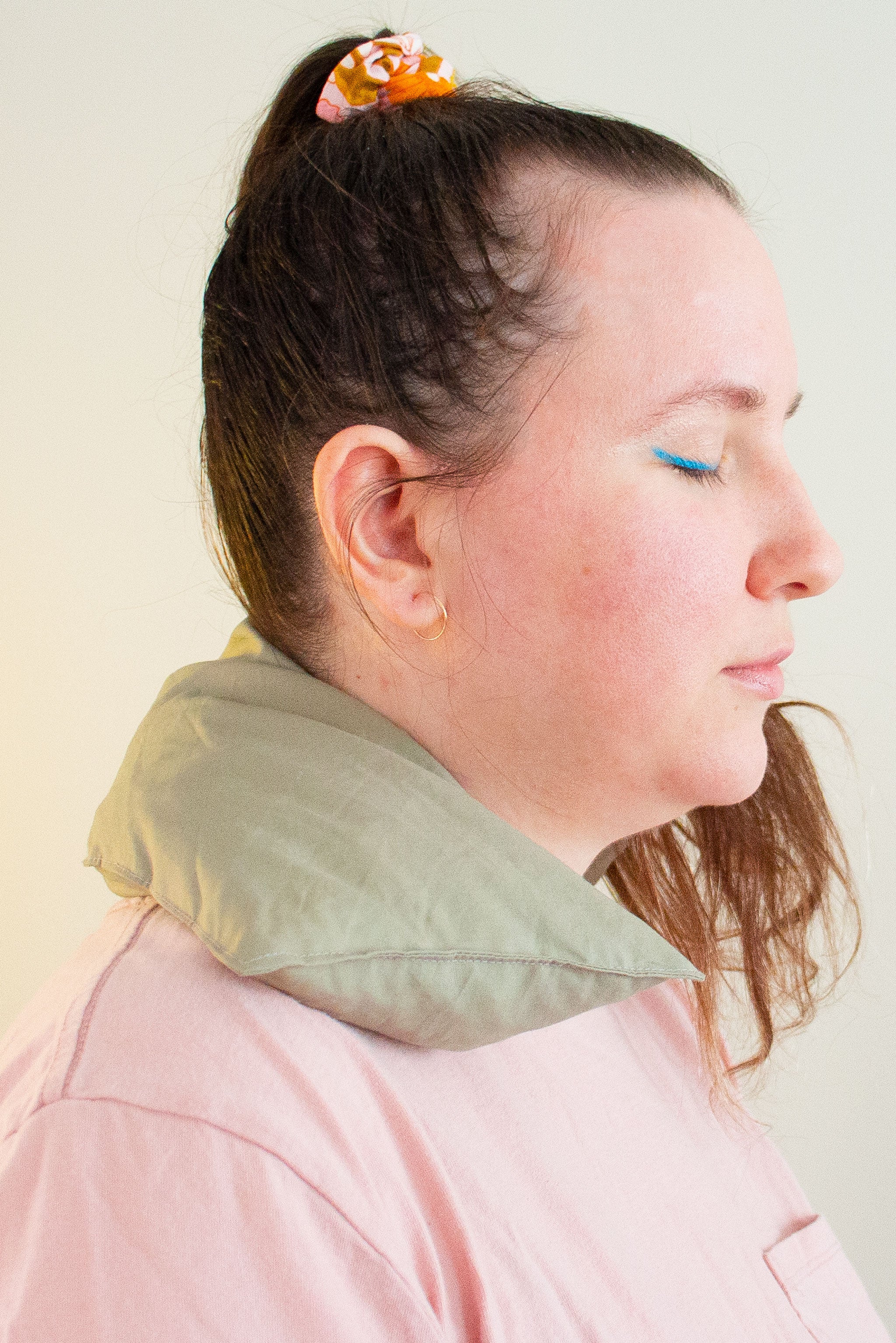 Profile of a woman with eyes closed wears a cherry pit grain bag around her neck.