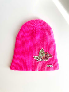 Hot pink knit hat with rose bush applique on bottom right. 