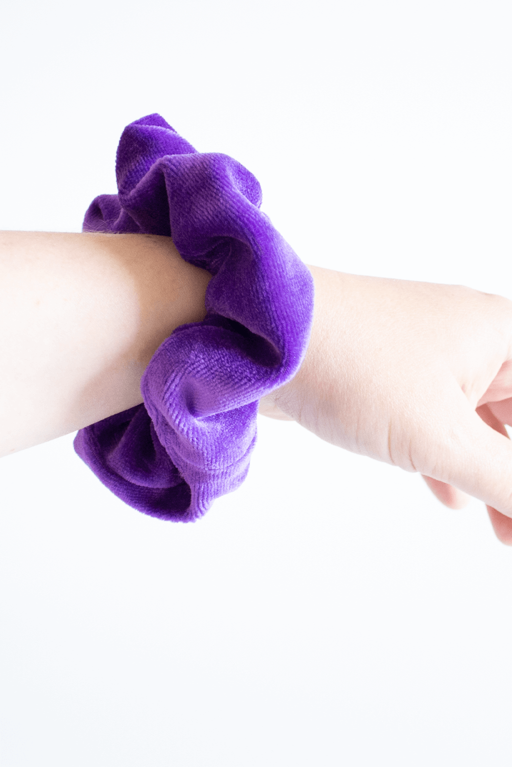 Purple velvet scrunchie worn on wrist.