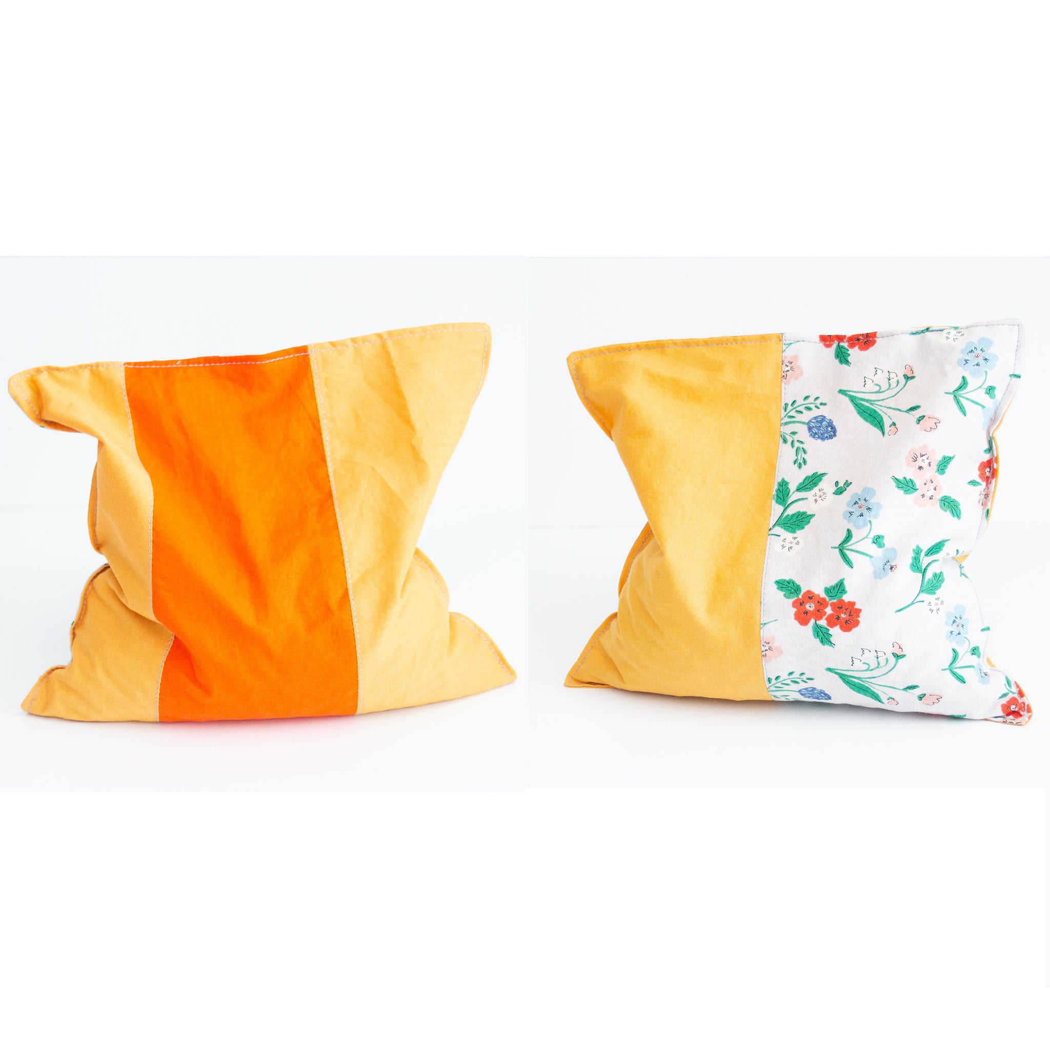 Two grain bags sit side by side showing front and back patchwork patterns. Front and back of patchwork (floral print and solid light and dark orange) rectangle cherry pit grain bag. Sit on white background.