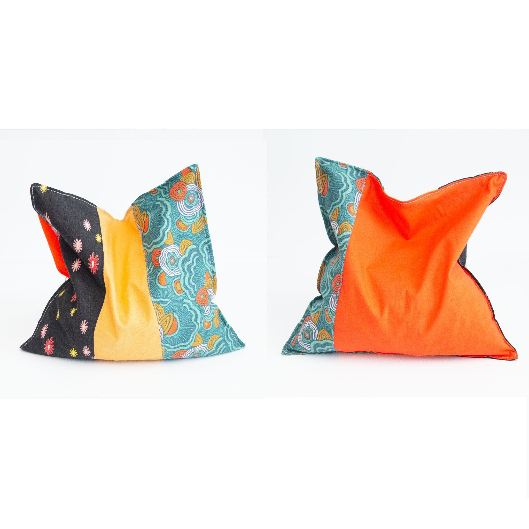 Two grain bags sit side by side showing front and back patchwork patterns. Front and back of patchwork (a mix of floral print, geometric print and solid light and dark orange) rectangle cherry pit grain bag. Sit on white background.