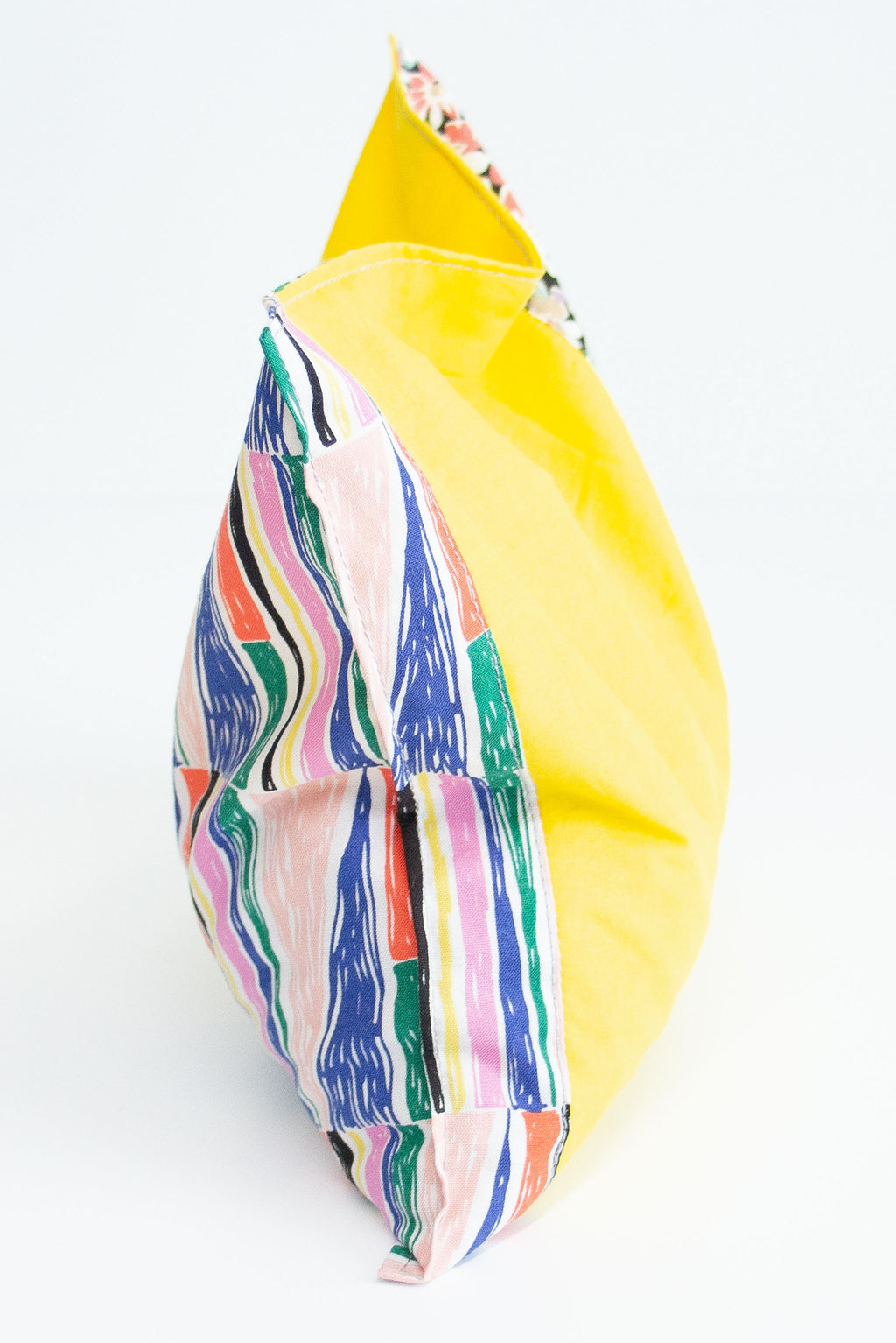 Rectangle cherry pit grain bag with geometric print and yellow patchwork sits on white background.