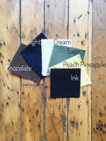 Load image into Gallery viewer, Zippered pouch fabric swatches: brown (chocoloate), navy blue (midnight), cream, (sage) green, orange yellow print (peach pineapple), and black (ink). 
