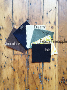 Zippered pouch fabric swatches: brown (chocoloate), navy blue (midnight), cream, (sage) green, orange yellow print (peach pineapple), and black (ink). 