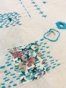 Close up of visible mending on muslin fabric.